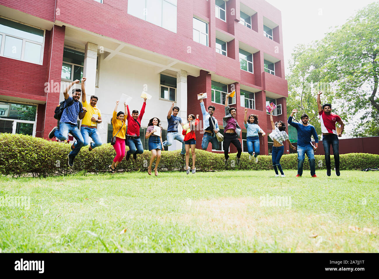 Il gruppo di college di ragazzi e ragazze studenti amici salto Mid-Air In-Outdoor edificio del campus Foto Stock