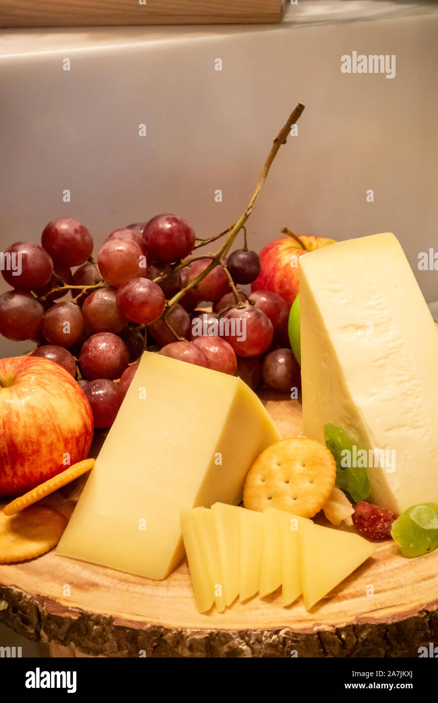 Formaggio gruviera con varietà di frutta e cracker sul piatto di legno in linea a buffet Foto Stock