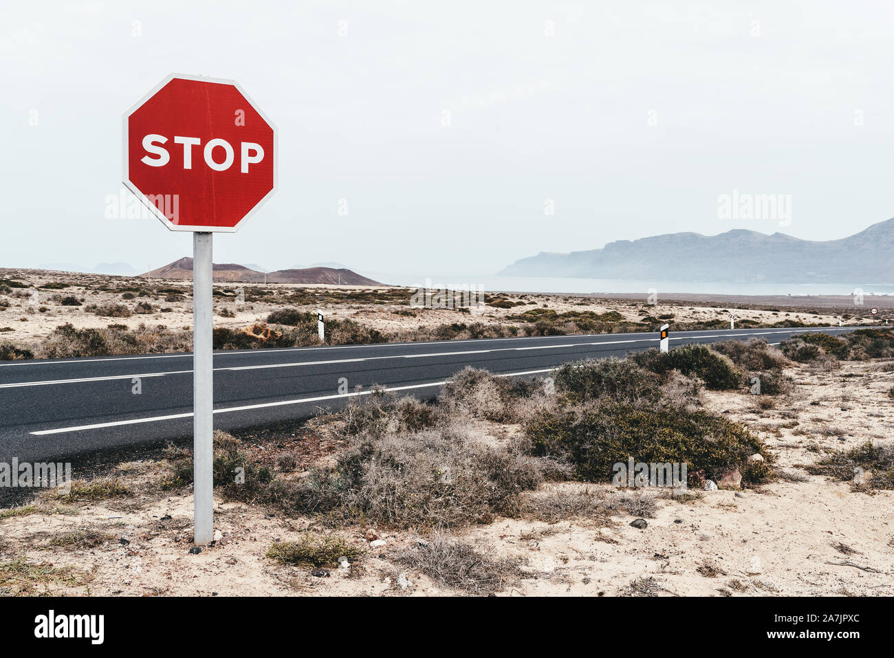 Il segnale di arresto in corrispondenza del bordo della strada attraverso arido paesaggio a Lanzarote isole Canarie Foto Stock