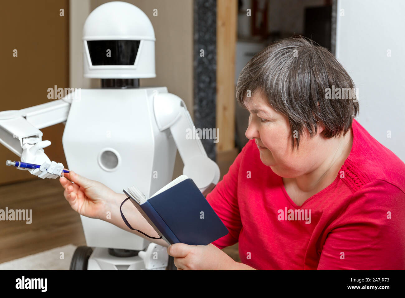 Robot friend è imparare o insegnare con un mentalmente donna disabile, raggiungendo la sua una matita Foto Stock