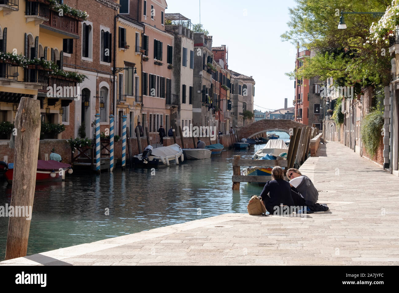 Un paio di parlare su un tranquillo canale street come visto dalla porta di Palazzoo Cini, un piccolo museo a Venezia Italia. Foto Stock