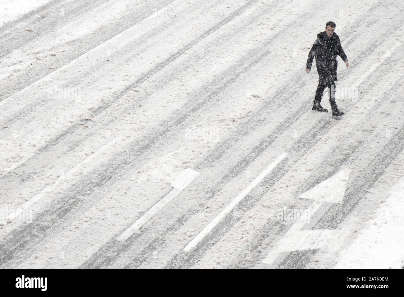 Belgrado, Serbia- 26 Gennaio 2019: Un uomo attraversare la strada al di fuori del crosswalk durante la tempesta di neve e di una vettura di pilotaggio, ad alto angolo di visione Foto Stock