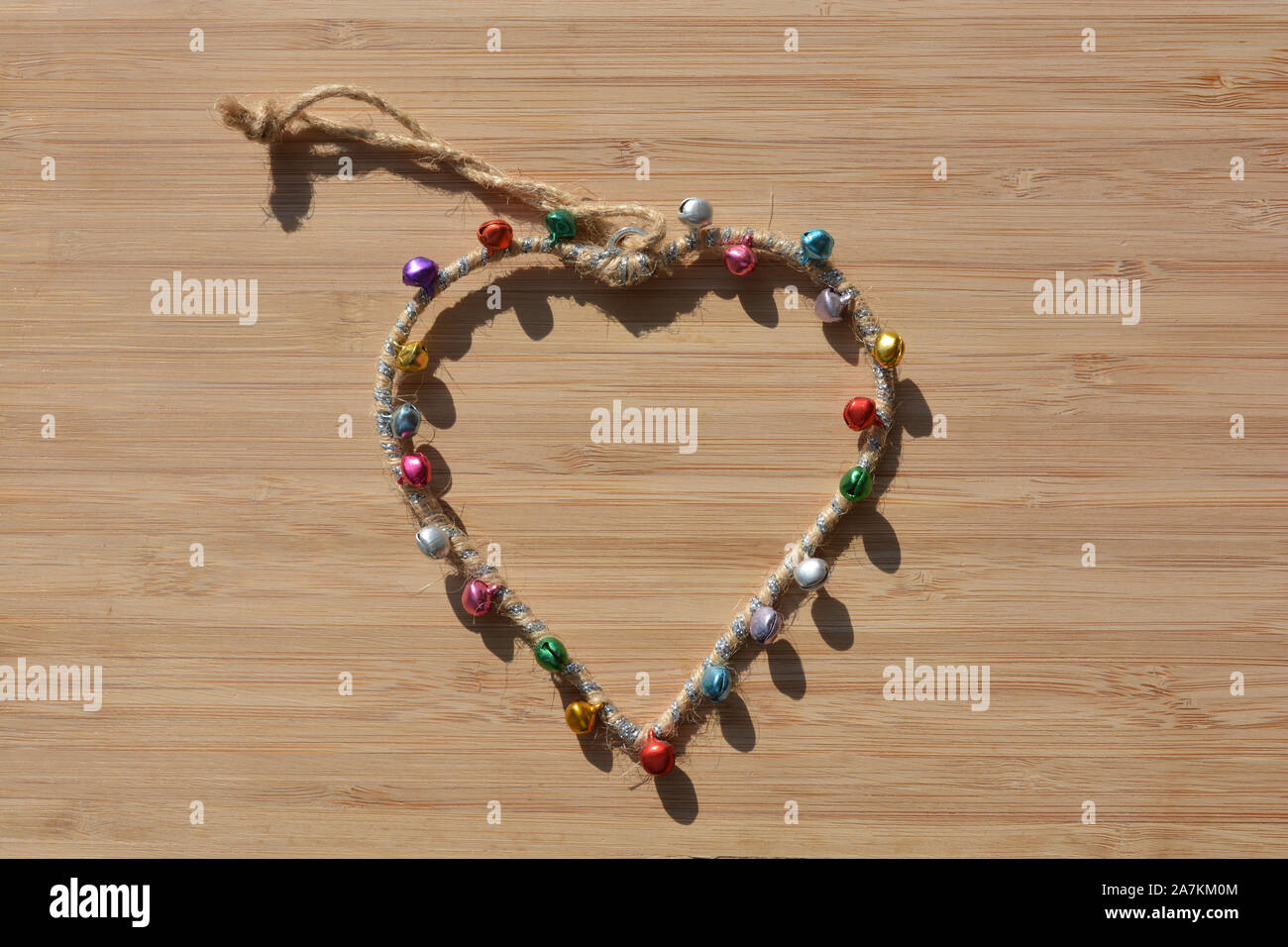 A forma di cuore, telaio hanging ornamento con campane su di un legno di bambù sfondo con copia spazio. Foto Stock