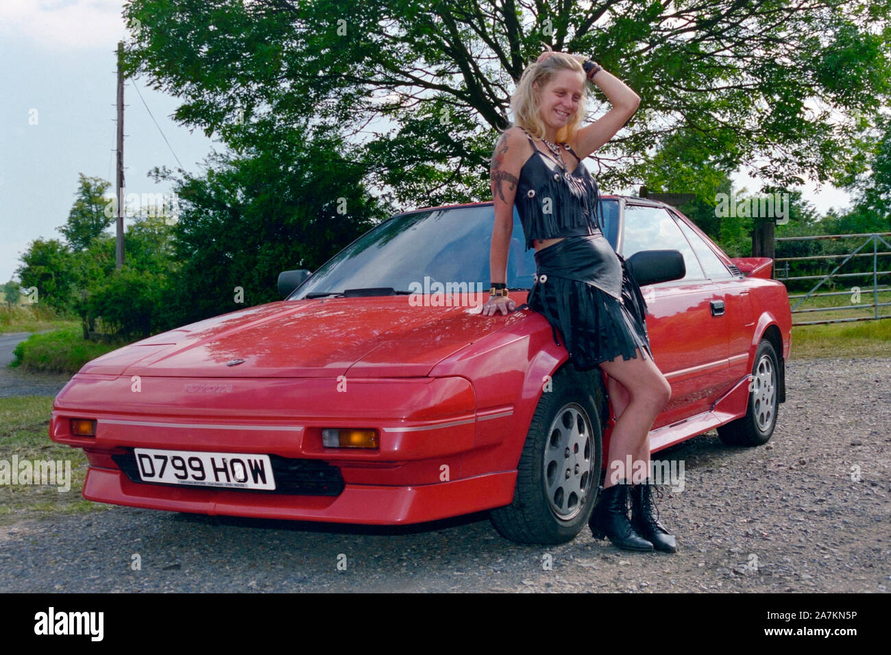 Ponendo femminile accanto a un rosso originale toyota mr2 MK1 alla fine degli anni novanta Inghilterra HAMPSHIRE REGNO UNITO Foto Stock