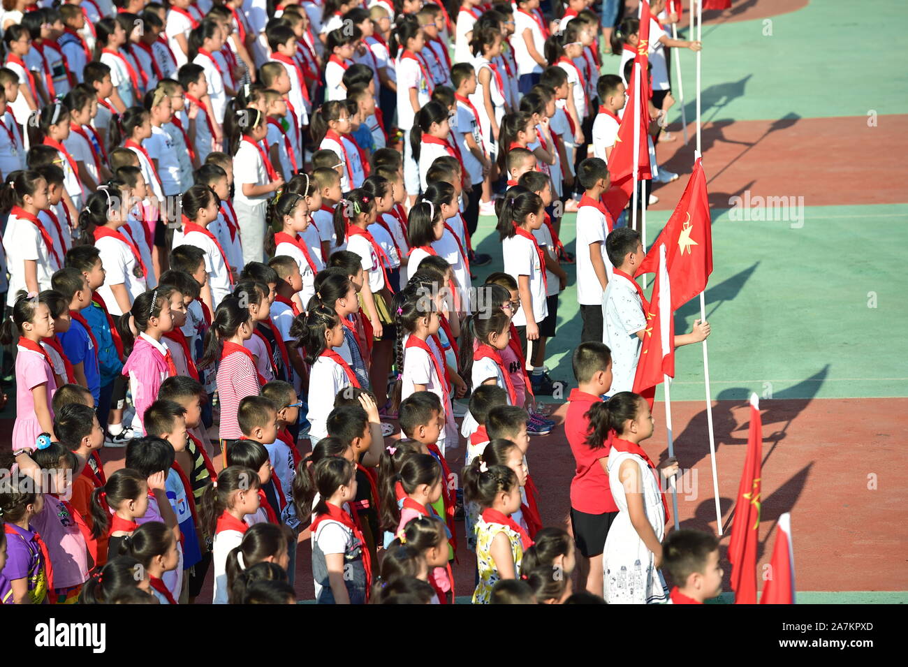 Giovani studenti cinesi che indossa il rosso sciarpe di giovani pionieri  della Cina assistere alla cerimonia di apertura per il nuovo semestre  presso una scuola primaria in S Foto stock - Alamy