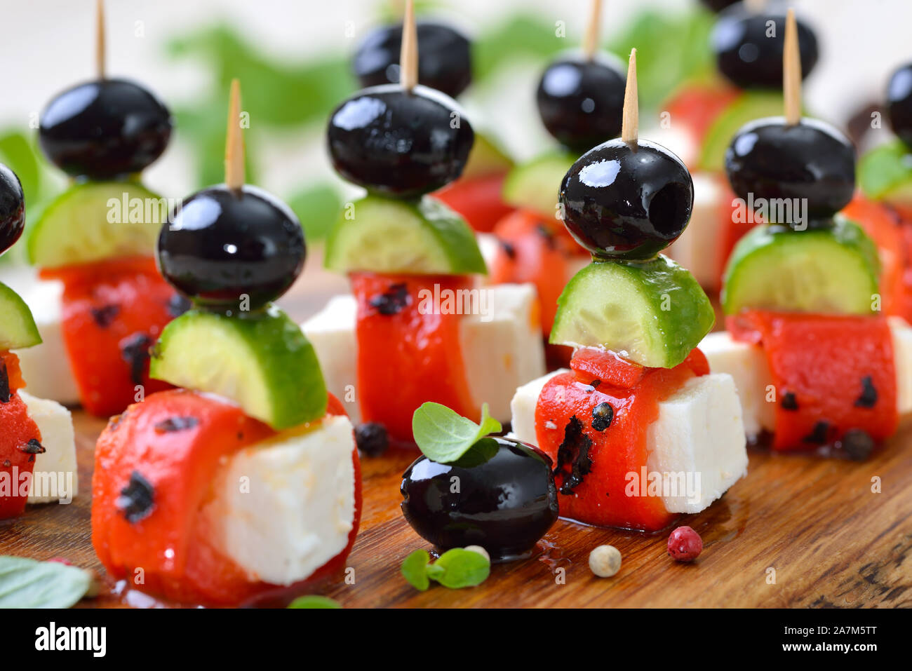 Antipasti greco: il formaggio Feta spiedini con grigliate e decapati peperoni rossi, snack cetrioli e olive nere,servita come decorazione di finger food antipasti Foto Stock