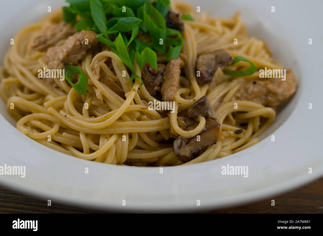 Cremosa di spaghetti con pollo e funghi misti. Irrorate con cipolline tagliate ad anelli. Preparate di fresco e servito come un sano e pasto veloce Foto Stock