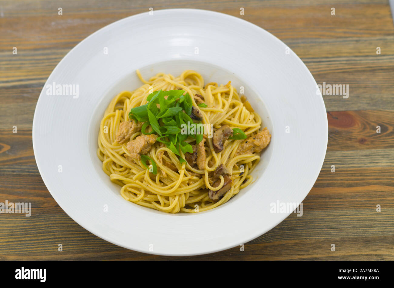 Cremosa di spaghetti con pollo e funghi misti. Irrorate con cipolline tagliate ad anelli. Preparate di fresco e servito come un sano e pasto veloce Foto Stock
