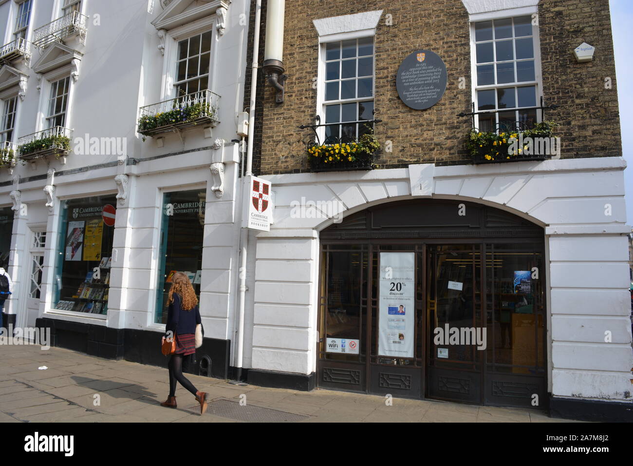 Giovane donna camminare passato Cambridge University Press bookshop, Cambridge, Cambs., Inghilterra Foto Stock