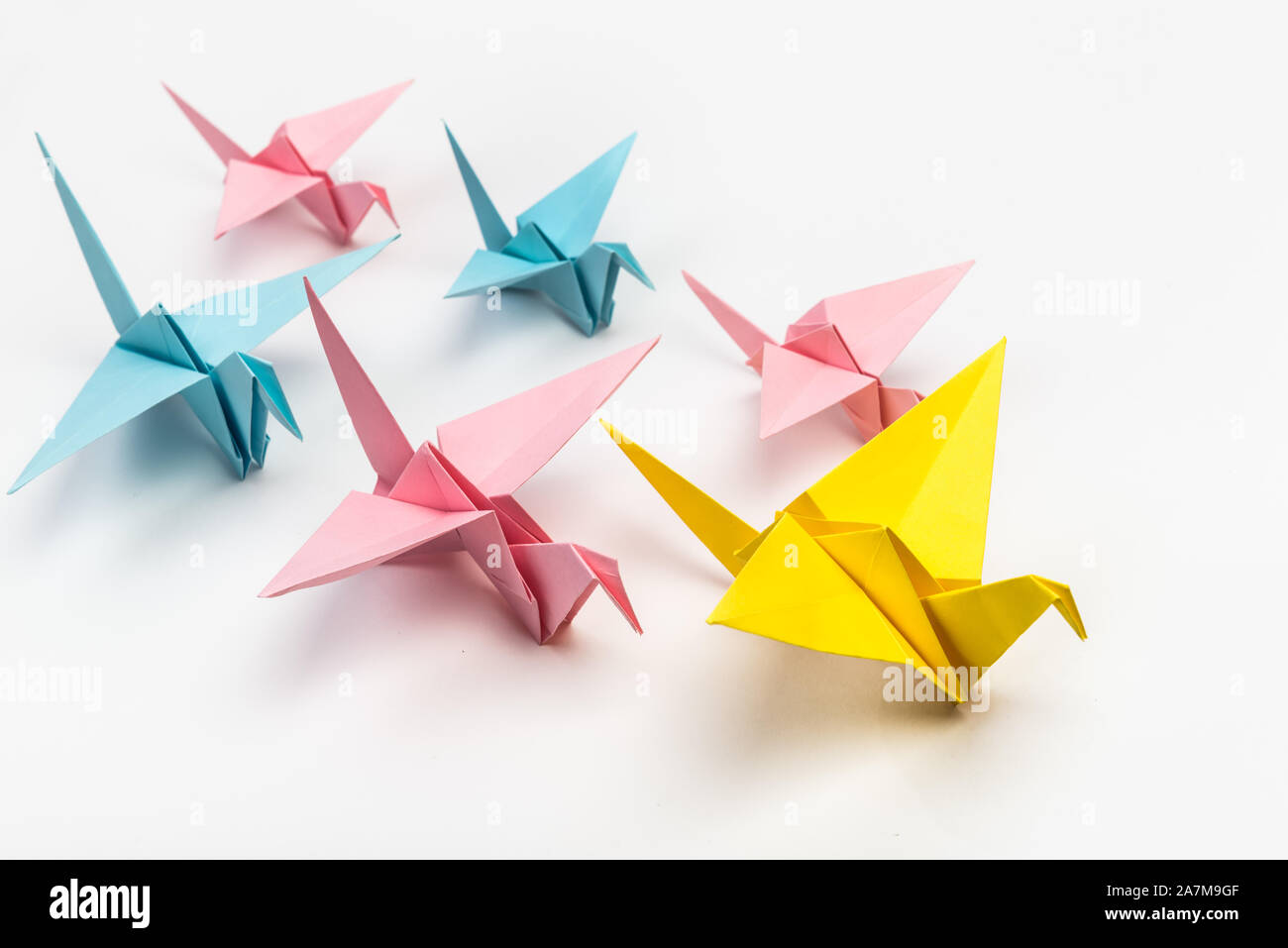 Origami uccelli gregge e leader di colore giallo su sfondo bianco. Il concetto di leadership. Giapponese carta ripiegata swan Foto Stock