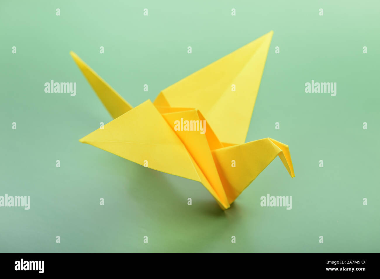 Origami bird su sfondo verde. Giapponese carta ripiegata Swan. Pace e simbolo di speranza Foto Stock