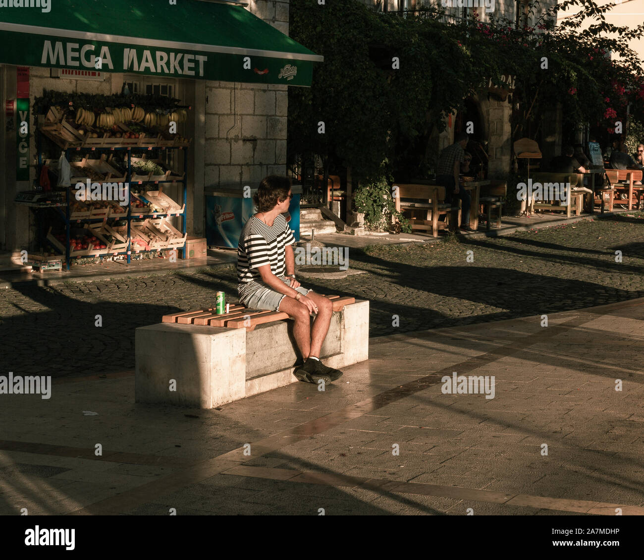 Guy godendo il sole sul banco a mare a Herceg Novi, Montenegro. Foto Stock