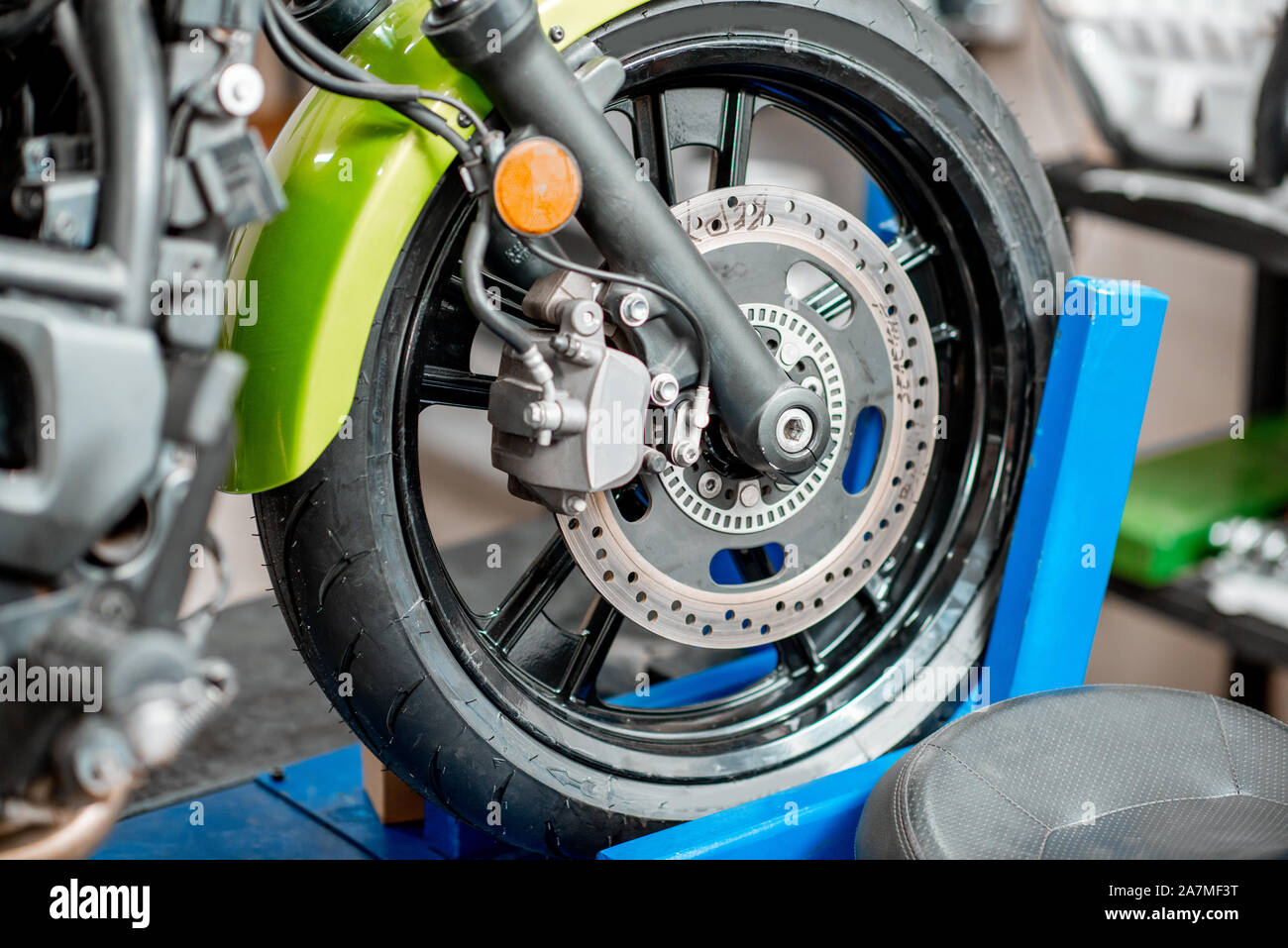 Close-up di una ruota di una motocicletta sportiva in piedi su un ponte elevatore durante la manutenzione in officina Foto Stock