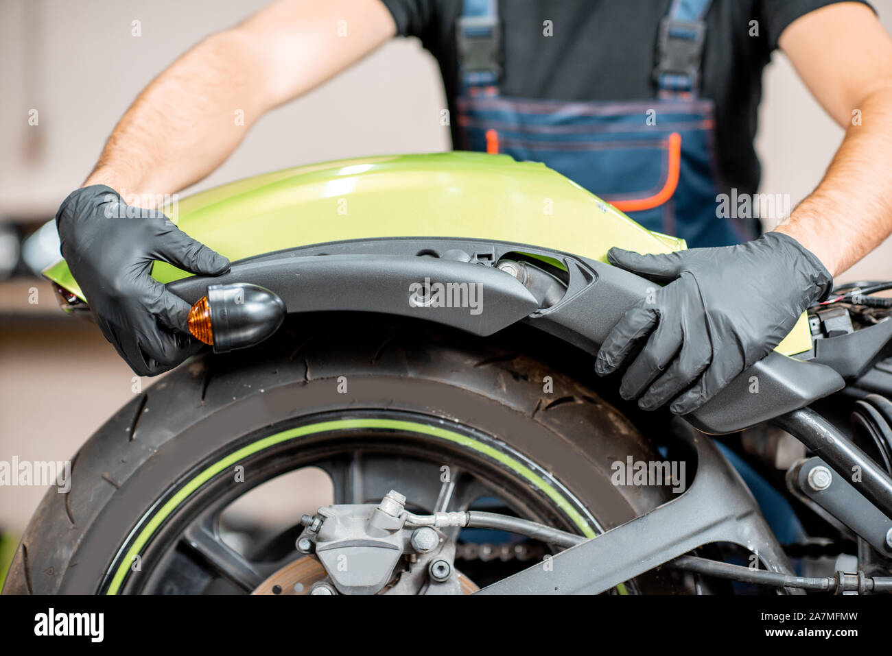 Close-up di lavoratore di montaggio parafango moto dopo una riparazione in officina. Concetto di riparazione e manutenzione di motocicli Foto Stock