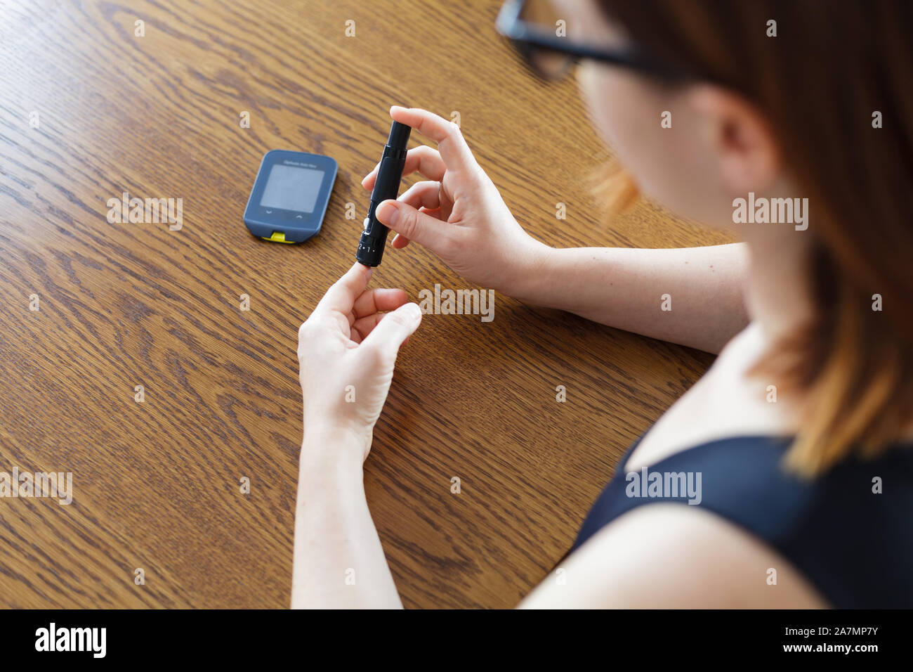Donna con lancetta a prendere il campione di sangue per controllare il livello di glucosio con il glucometro tradizionale Foto Stock