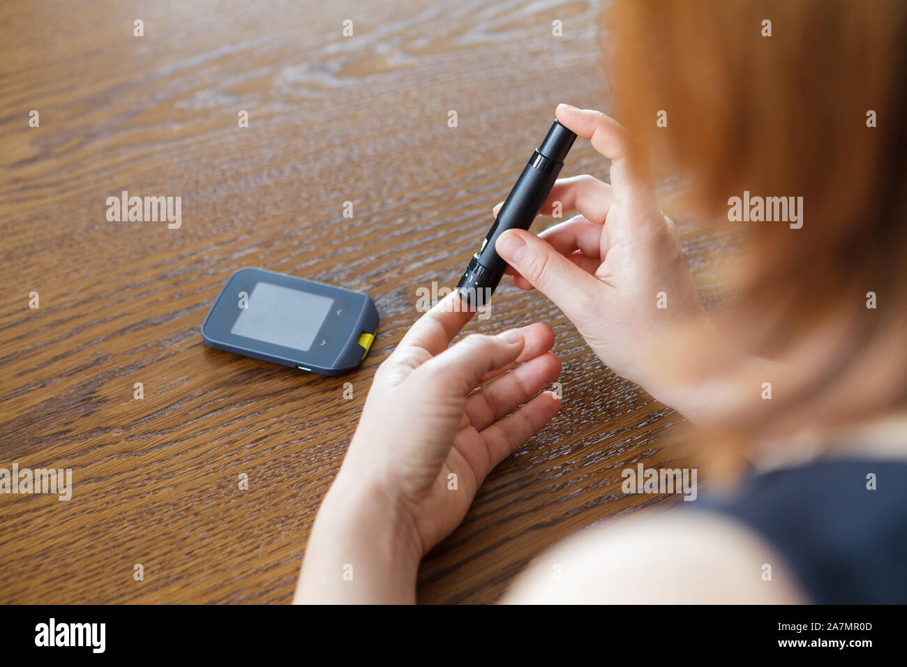 Donna con lancetta a prendere il campione di sangue per controllare il livello di glucosio con il glucometro tradizionale Foto Stock