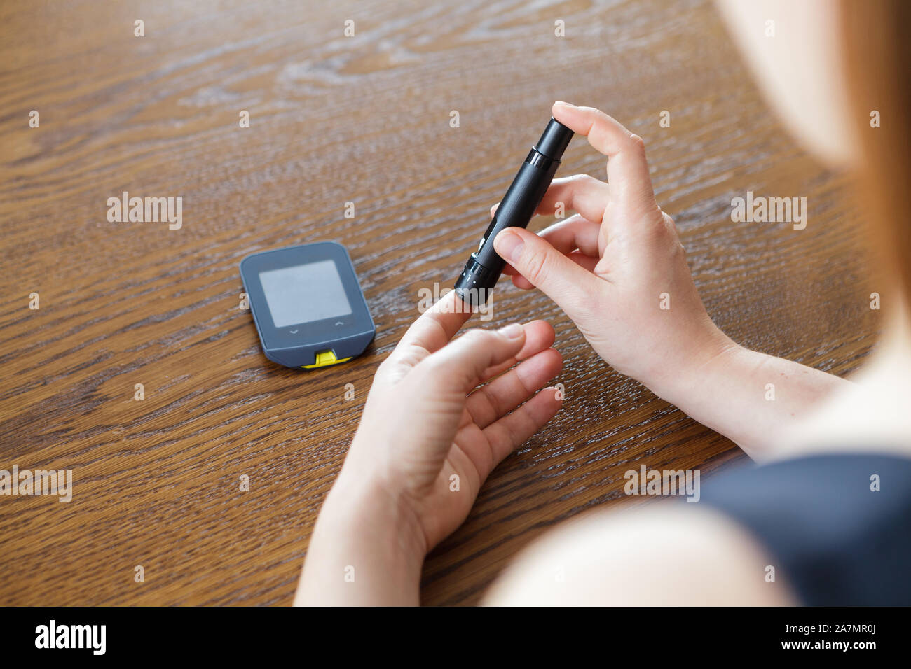 Donna con lancetta a prendere il campione di sangue per controllare il livello di glucosio con il glucometro tradizionale Foto Stock