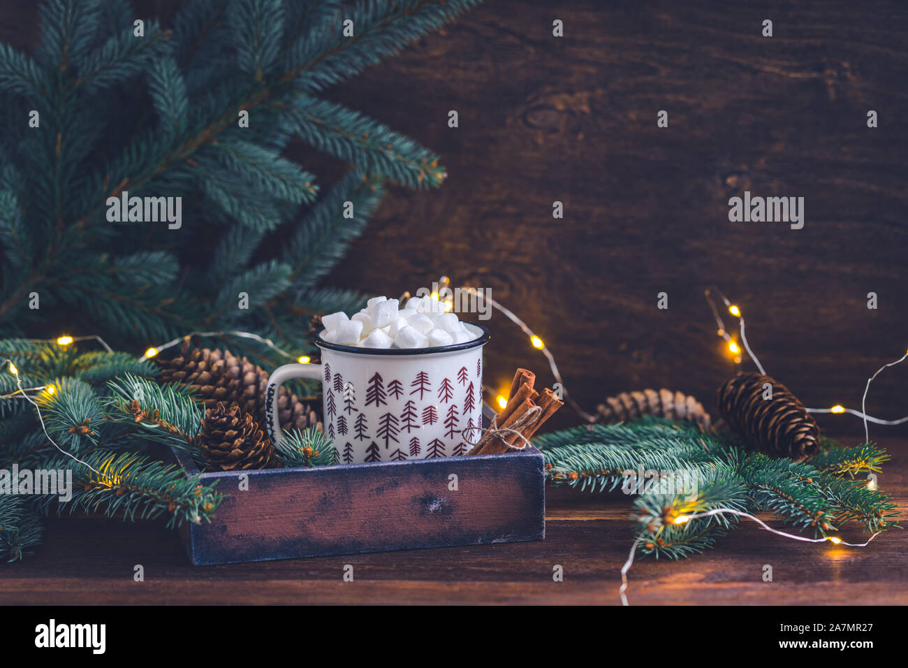 Abete colorato tazza ceramica con un caffè o una cioccolata calda con marshmallows sul luminoso sullo sfondo di legno con scintillante garland Foto Stock