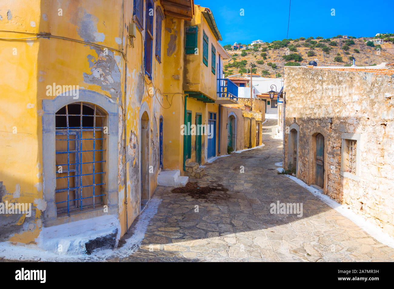 Strada stretta con coloratissime case di pietra nel vecchio villaggio di Pano Elounda, Creta, Grecia. Foto Stock
