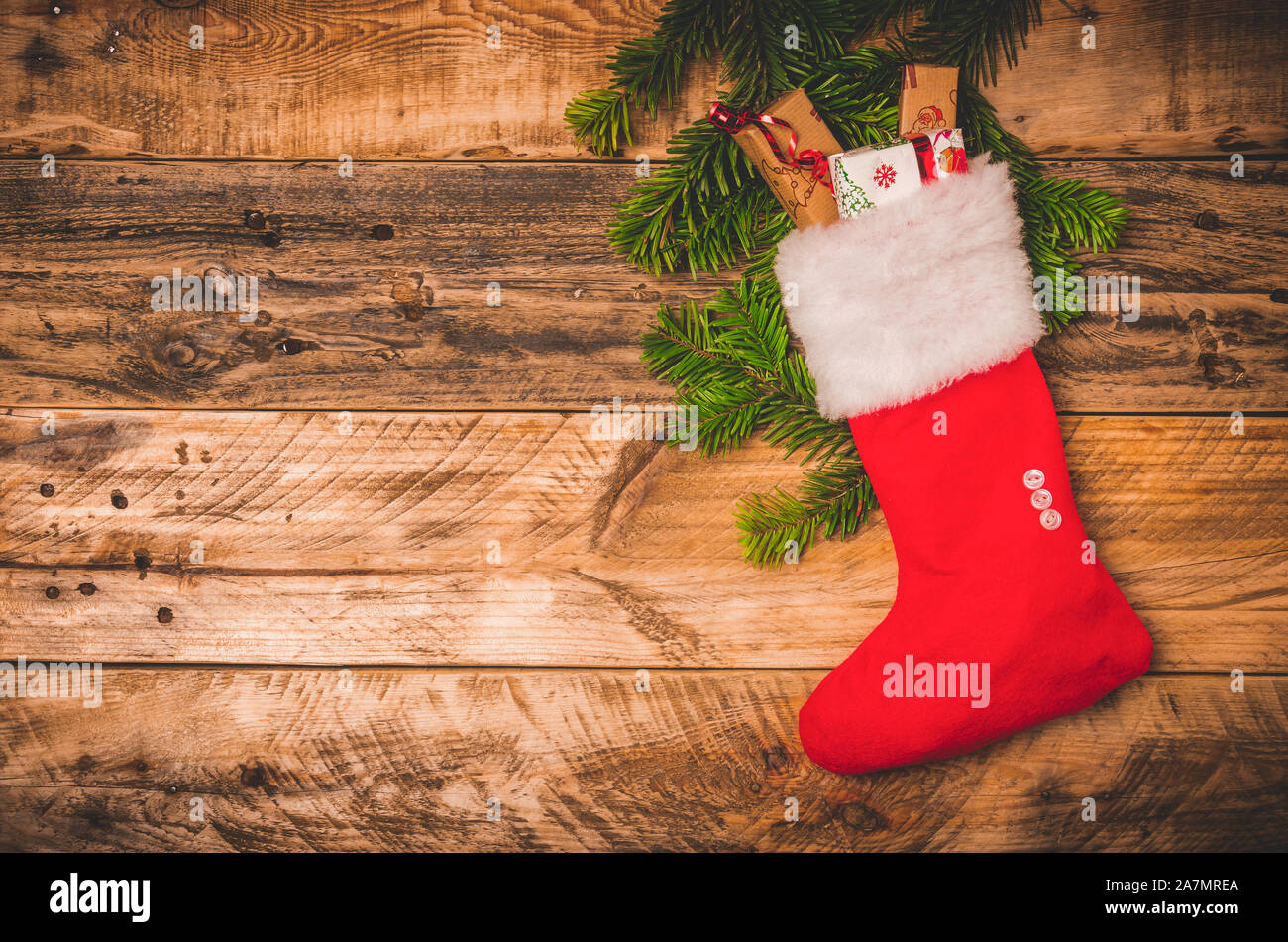 Natale calza rossa con pelliccia bianca e doni su una tavola di legno rustico sfondo. Appartamento laici o top view image con copia spazio. Foto Stock