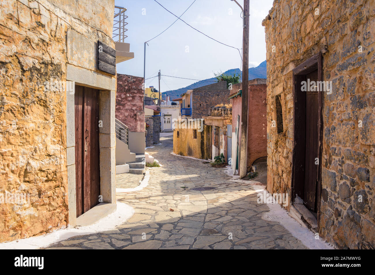 Strada stretta con coloratissime case di pietra nel vecchio villaggio di Pano Elounda, Creta, Grecia. Foto Stock
