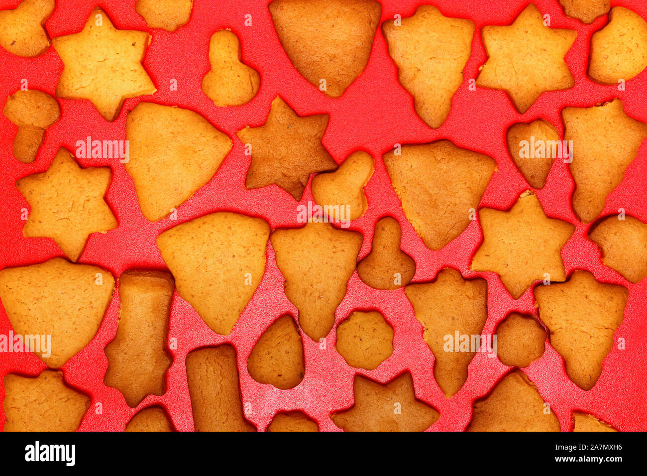 Festosa fatti a mano biscotti a forma di stelle, alberi di Natale, cuori, campane per Natale e Capodanno Vacanze su uno sfondo di colore rosso. Vista dall'alto. Foto Stock