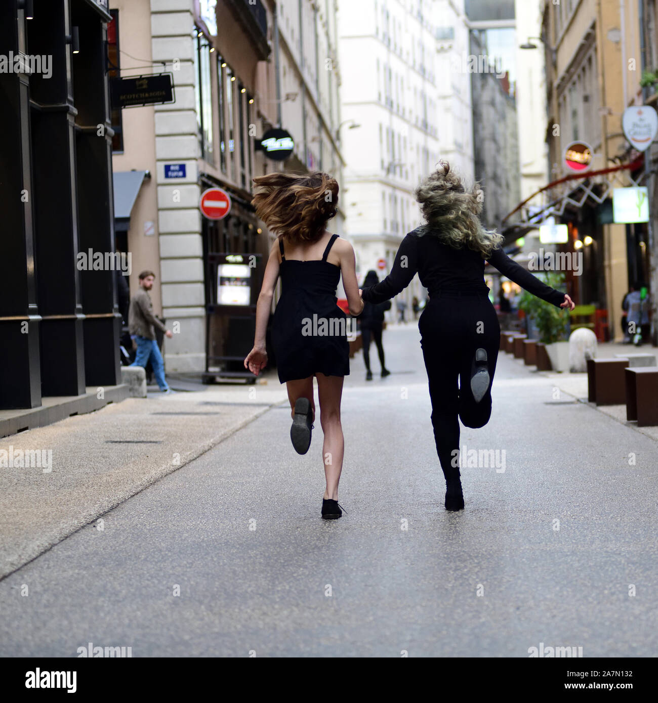Due ragazze in esecuzione giù per una strada a Lione Francia Foto Stock