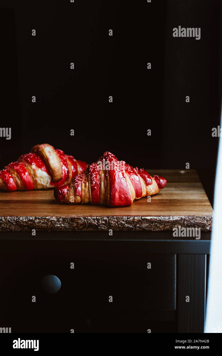 Due cornetti di ciliegio sono serviti in un ambiente rustico di legno. Moody cibo fotografia. Foto Stock