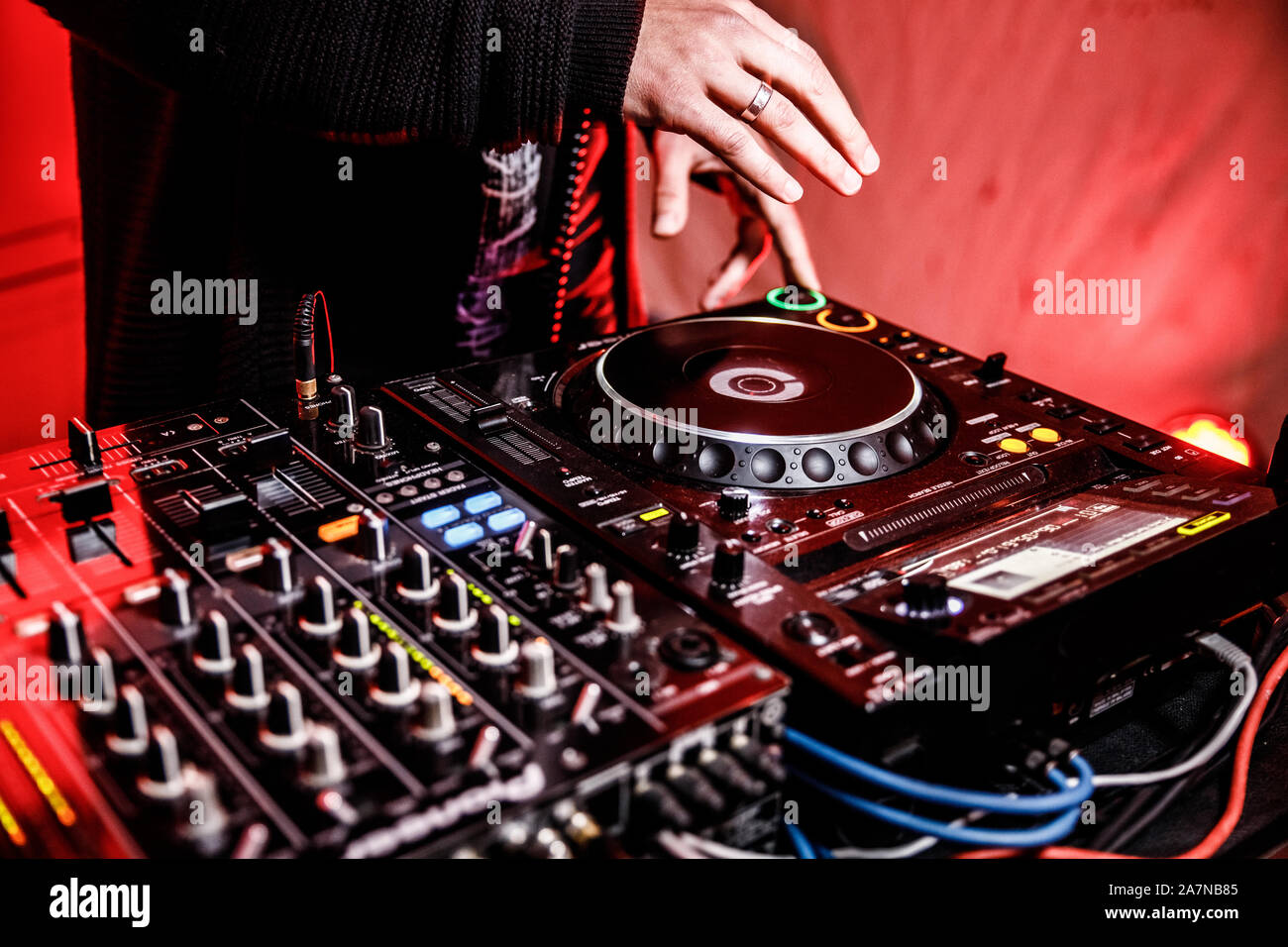 DJ suona live set e mixare la musica sulla console di piattaforma girevole nella fase nei night club. Disc Jokey le mani su un mixer audio station al club di partito. DJ Mixer Foto Stock