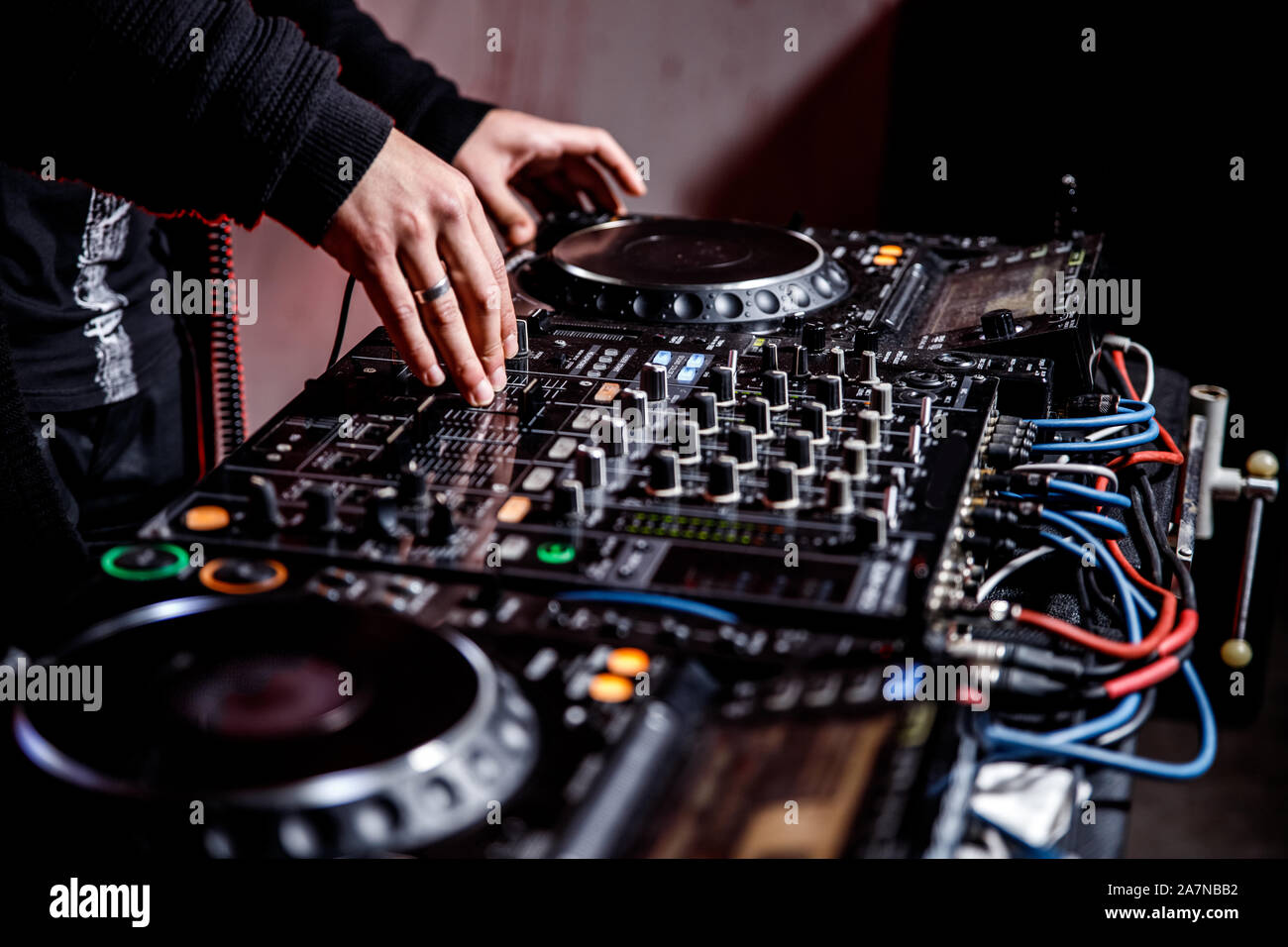 DJ suona live set e mixare la musica sulla console di piattaforma girevole nella fase nei night club. Disc Jokey le mani su un mixer audio station al club di partito. DJ Mixer Foto Stock
