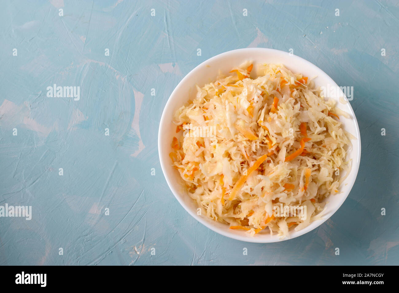 Crauti fatti in casa con le carote in una ciotola su un fondo azzurro, alimento fermentato, vista dall'alto Foto Stock