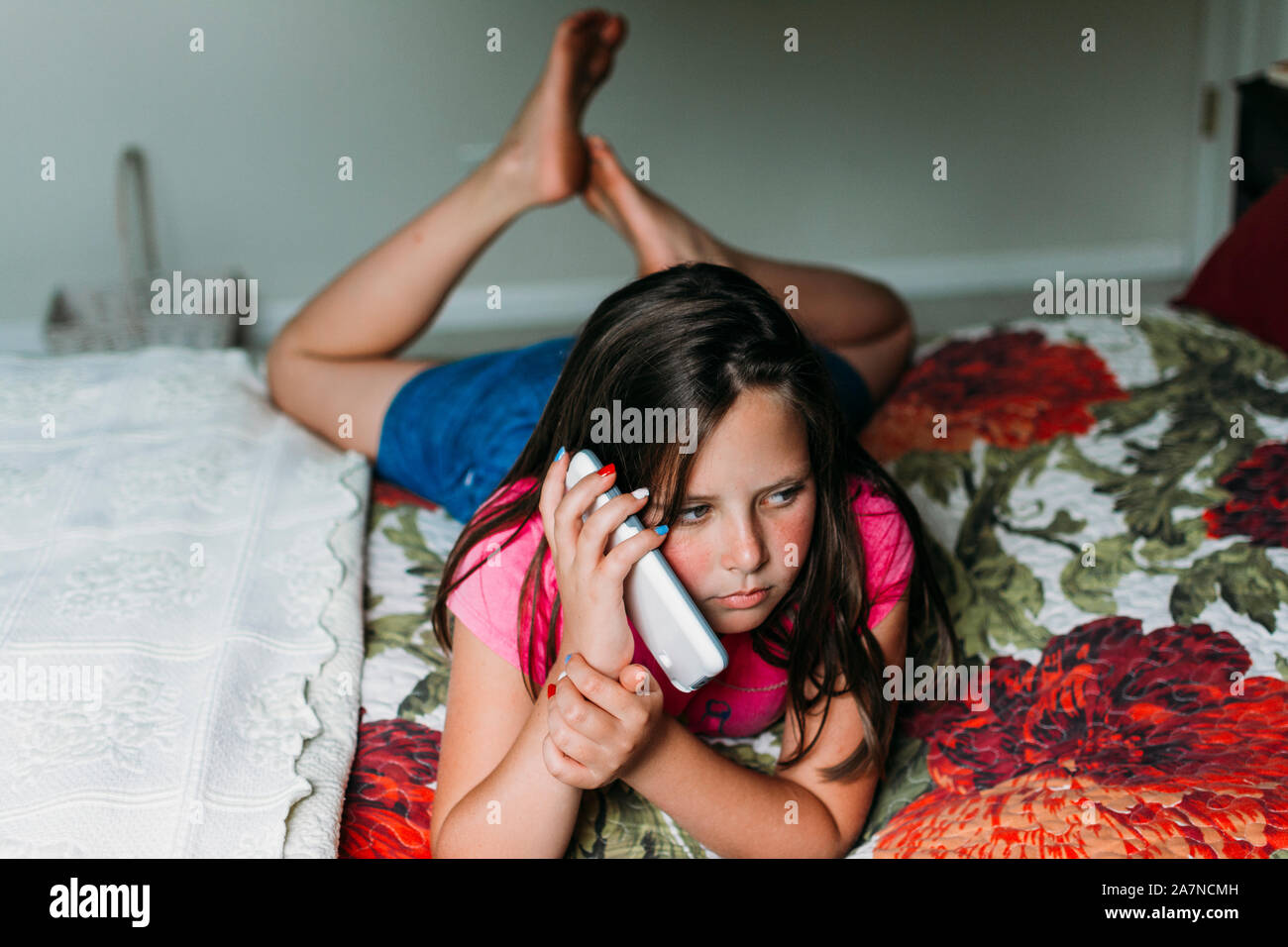 Teen ragazza rilassante su un letto di parlare sul suo telefono cellulare Foto Stock