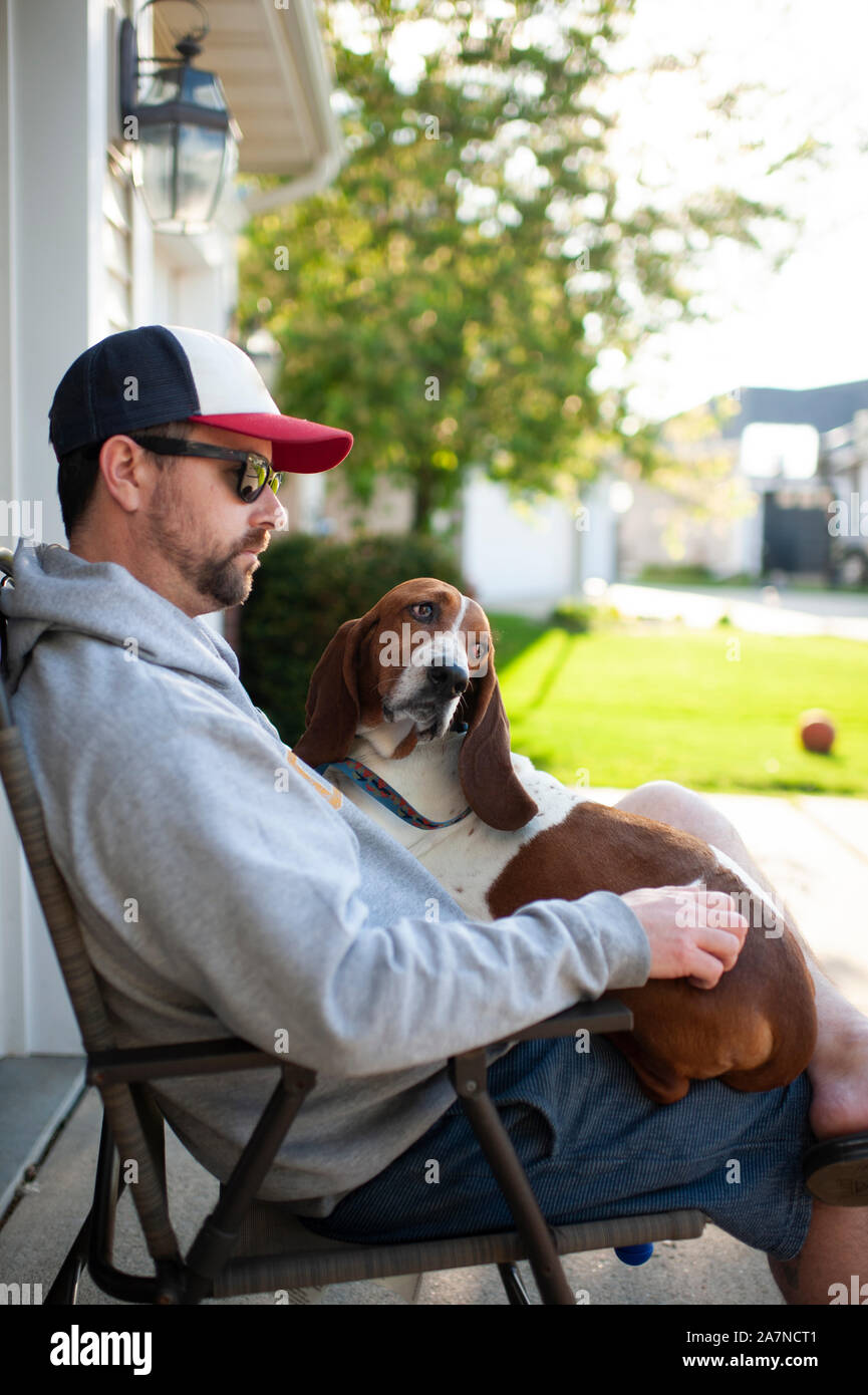L'uomo 30-40 anni seduto nella sedia con basset hound dog sul suo giro Foto Stock