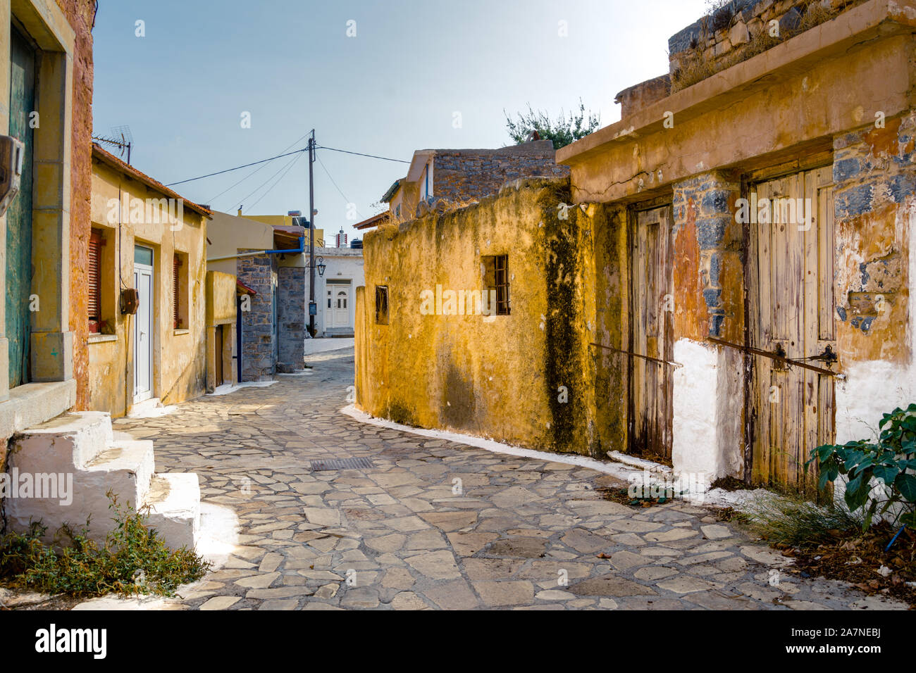 Strada stretta con coloratissime case di pietra nel vecchio villaggio di Pano Elounda, Creta, Grecia. Foto Stock