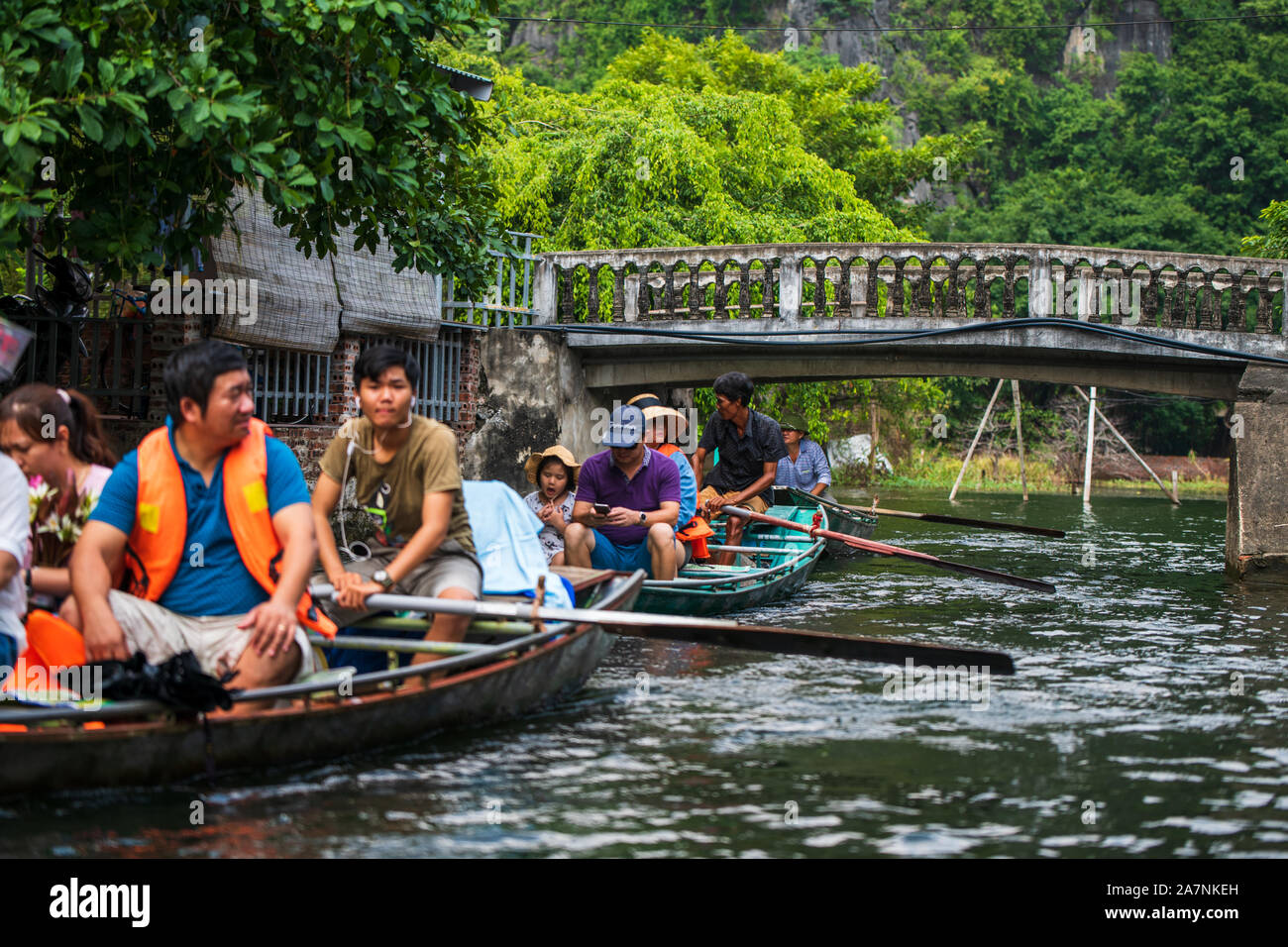Tam Coc, Vietnam, 16 Ottobre 2019: turisti asiatici un viaggio su una barca a remi tour attraverso le grotte di pietra calcarea di Ninh Binh in una giornata di sole Foto Stock