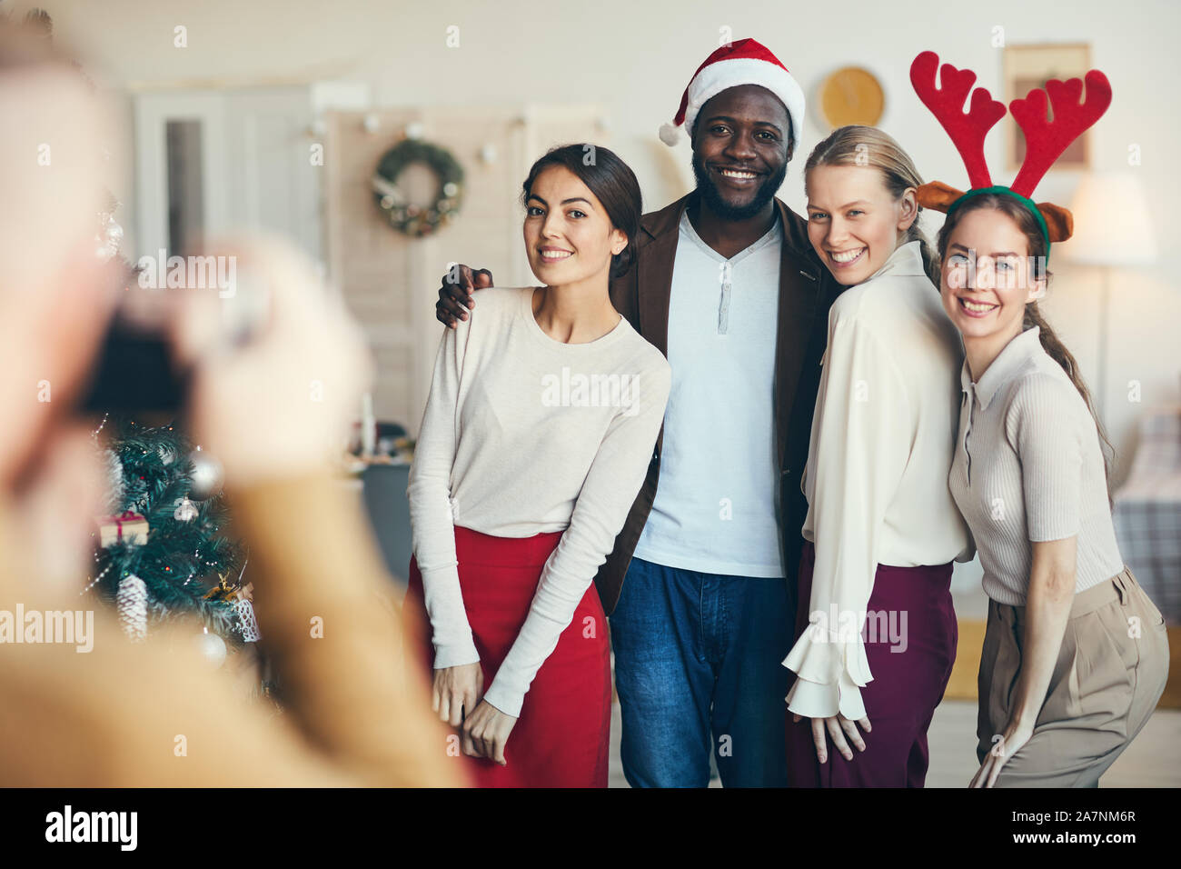 Multi-etnico gruppo di amici che posano per una foto durante la festa di Natale, tutti indossando cappelli di Babbo Natale e costumi, spazio di copia Foto Stock