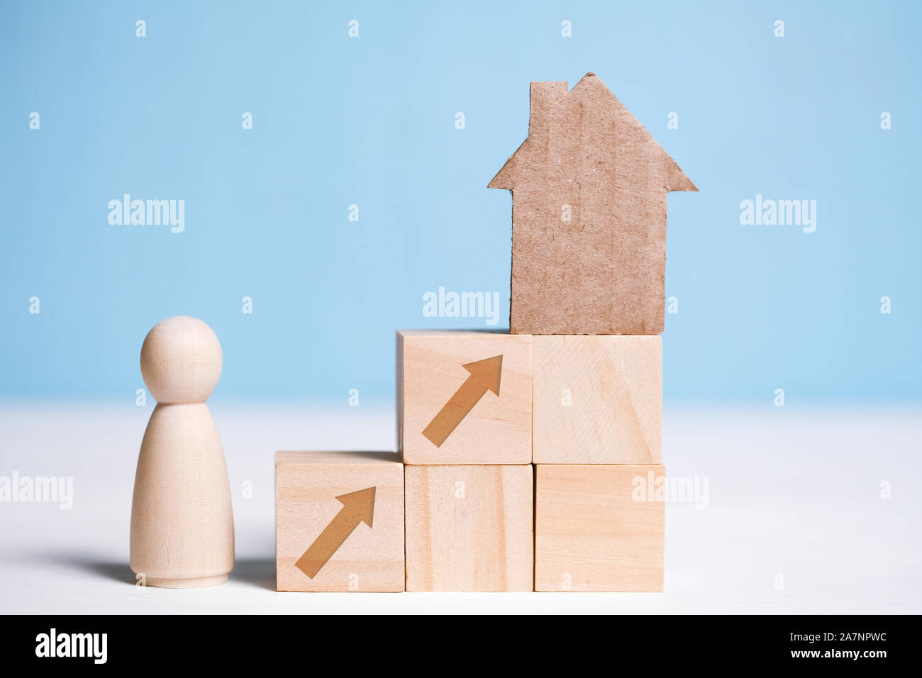 Abstract casa di cartone su cubi di legno e l'uomo. Il concetto di acquisto di una casa come un obiettivo. Close up. Foto Stock