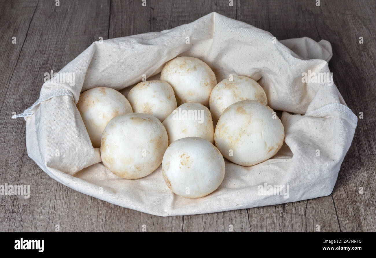 Close up di un mazzetto di greggio di funghi champignon su bianco borsa di canapa . Foto Stock