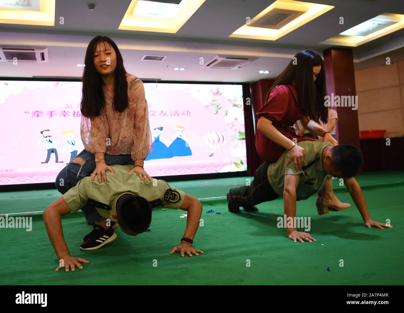 Gli uffici di polizia stanno facendo push-up con donne seduti sulle loro spalle durante il match-making evento in Nanchang City, a sud-est della Cina di Jiangxi provinc Foto Stock