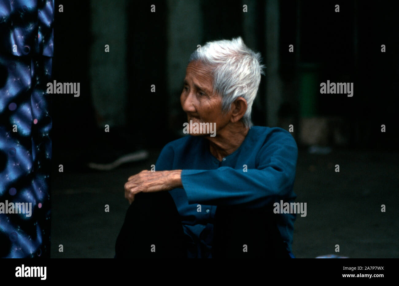 Un anziano uomo vietnamita seduto a lato di una strada nella città di Ho Chi Minh (Saigon), Vietnam. Foto Stock