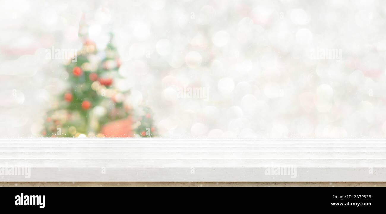 Vuoto in legno bianco tavolo con abstract e accogliente soggiorno con decor di albero di natale luce stringa la sfocatura dello sfondo con la neve,sfondo vacanze,Mock up ba Foto Stock