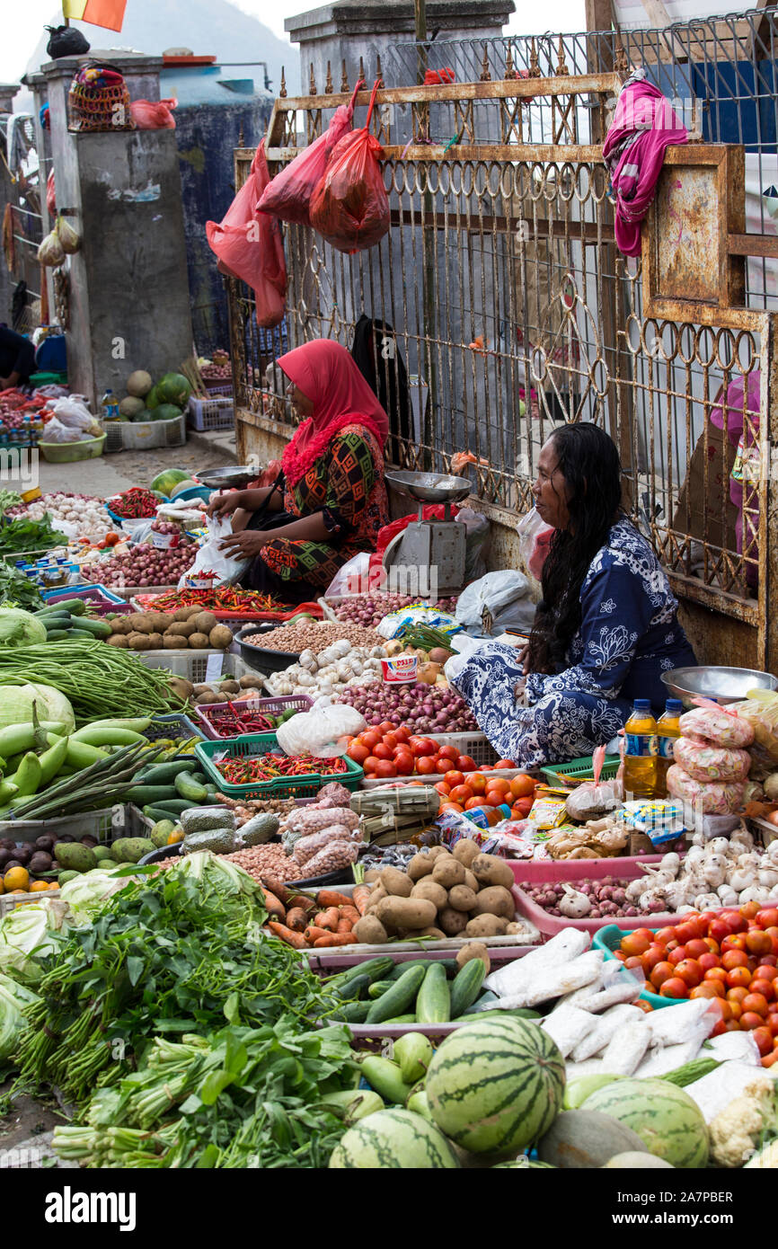 Labuanbajo, Indonesia - Agosto 17, 2015: gruppo non identificato di donne che indossano hijab e guarnizioni tradizionali vendono frutta tropicale in strada Foto Stock