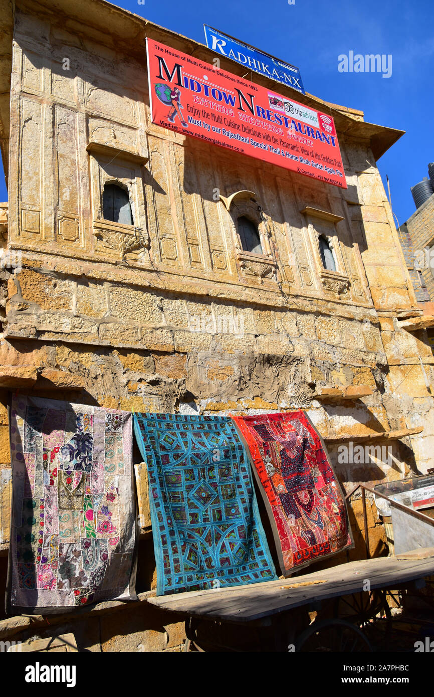 Tappeto indiano shop sotto ornato oro edificio in arenaria, Jaisalmer, Rajasthan, India Foto Stock