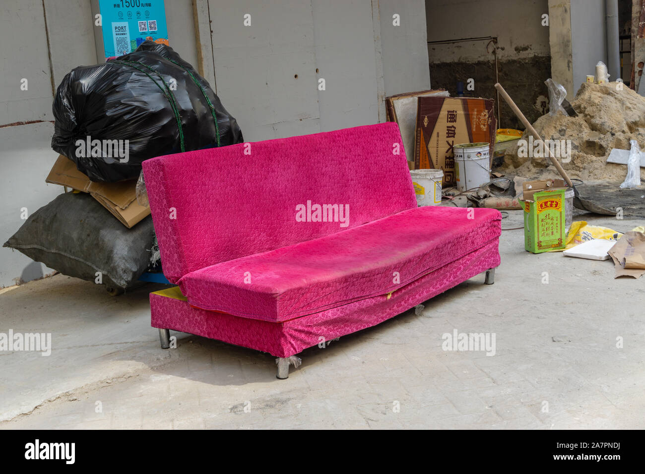 Vecchio divano rosa sul marciapiede Foto Stock