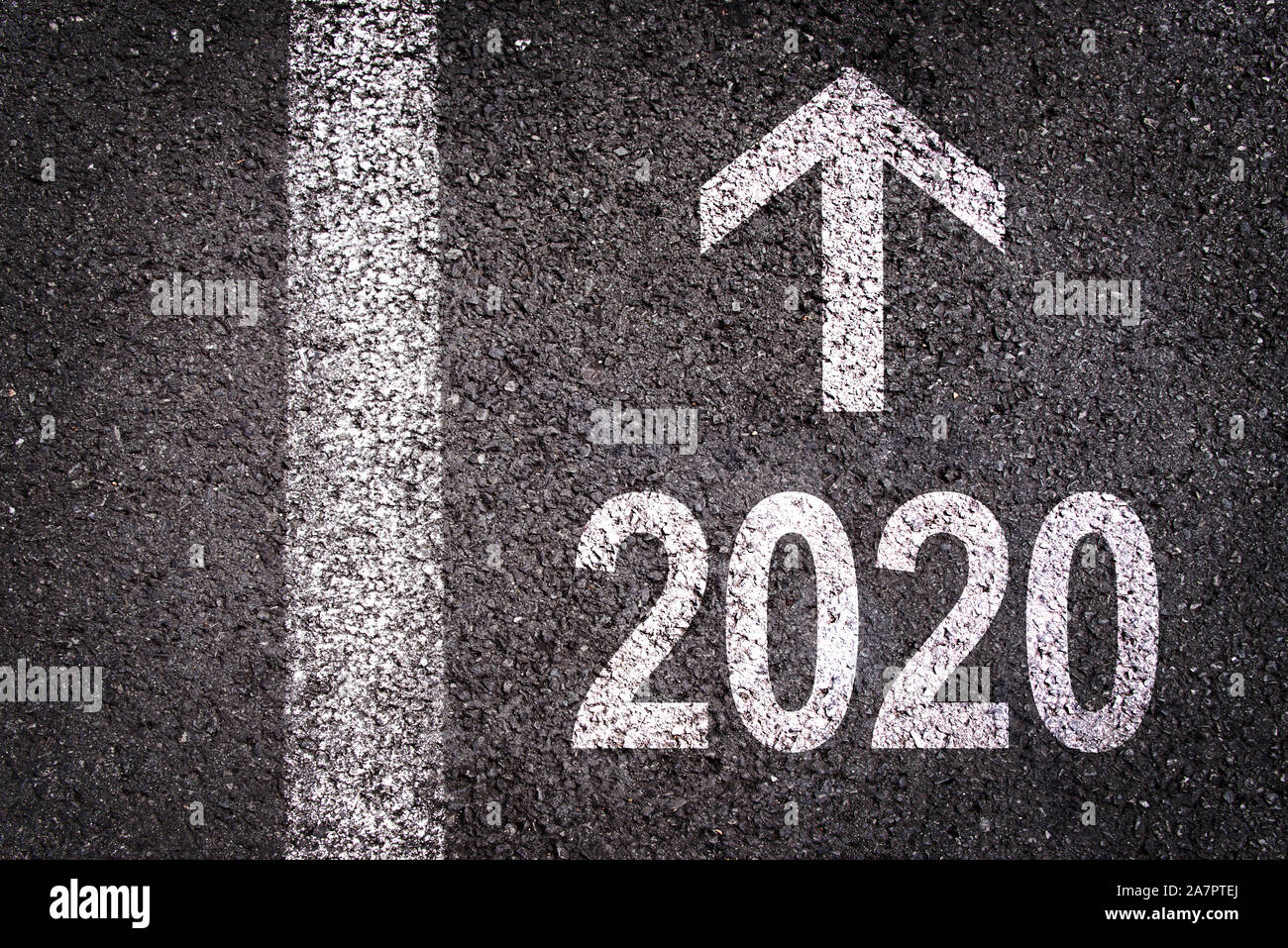 2020 e una freccia di direzione scritto su una strada asfaltata di background urbano, anno nuovo biglietto di auguri Foto Stock