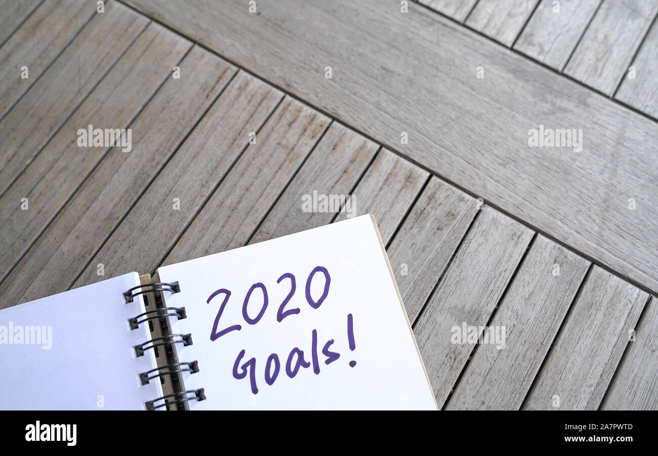 Nuovo anno 2020. La scrittura a mano con un pennarello di 2020 obiettivi sul blocco note. Vista dall'alto. Su un tavolo di legno. Foto Stock