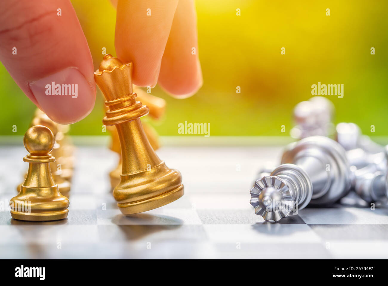 Re scacco matto giocatore di scacchi vincente gioco di bordo con il nemico giù sul verde esterno dello sfondo. Sfida aziendale vincitore concetto. Foto Stock