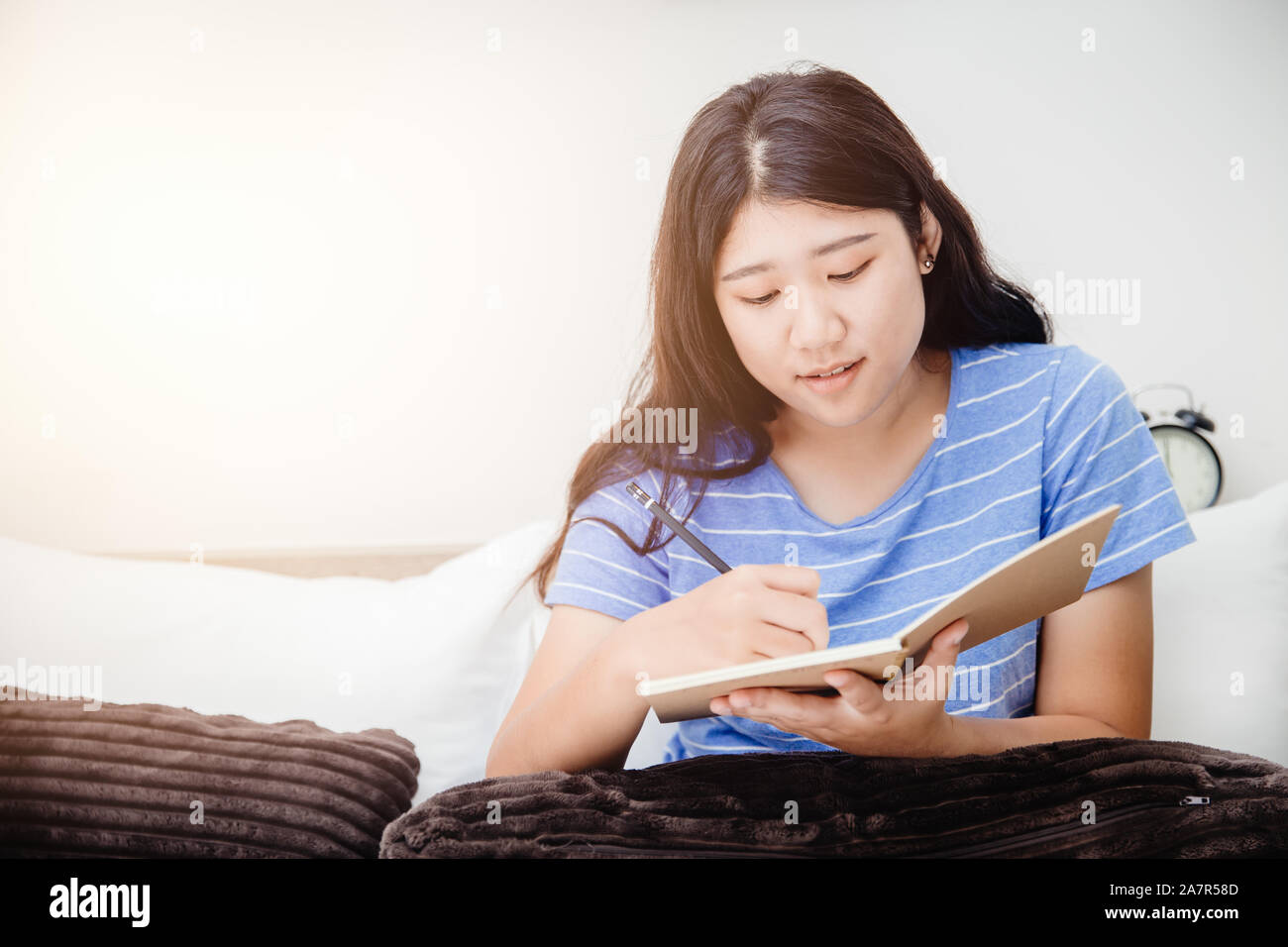 Girl Teen prendendo nota breve iscritto Lista da fare a letto quando il suo risveglio al mattino. Foto Stock