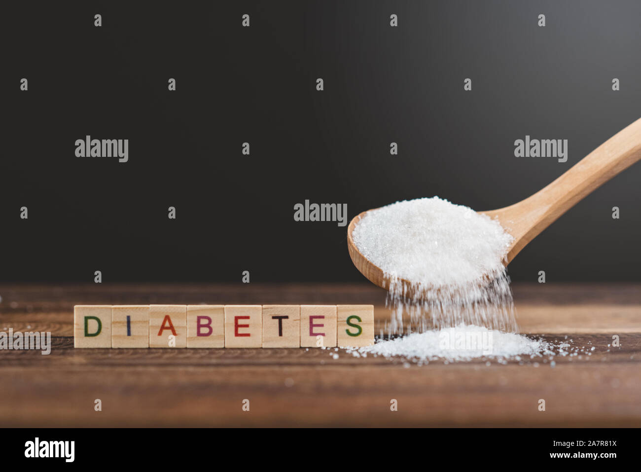 Lo zucchero versato su di un tavolo di legno con diabete di word. Concetto di diabete e malsano mangiare. Foto Stock