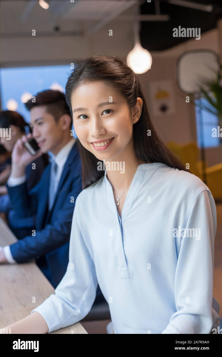 Ritratto di una giovane imprenditrice sorridente con il rettilineo capelli neri guardando la telecamera Foto Stock